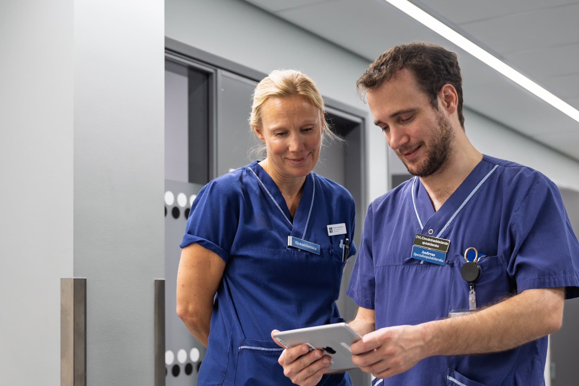 Kristina Lockne-Andersson och Andreas Schenström. Personal visar surfplatta och app.