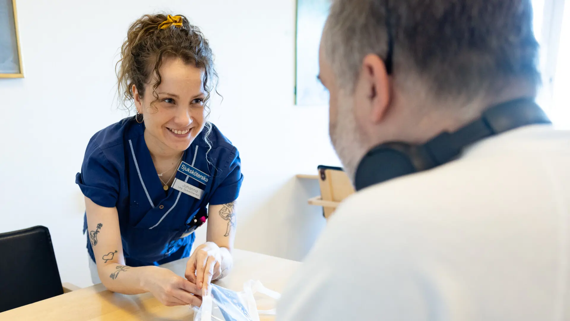 Johanna Riikonen hjälper en patient med telemetriövervakning en bärbar dosa som registrerar hjärtats rytm.