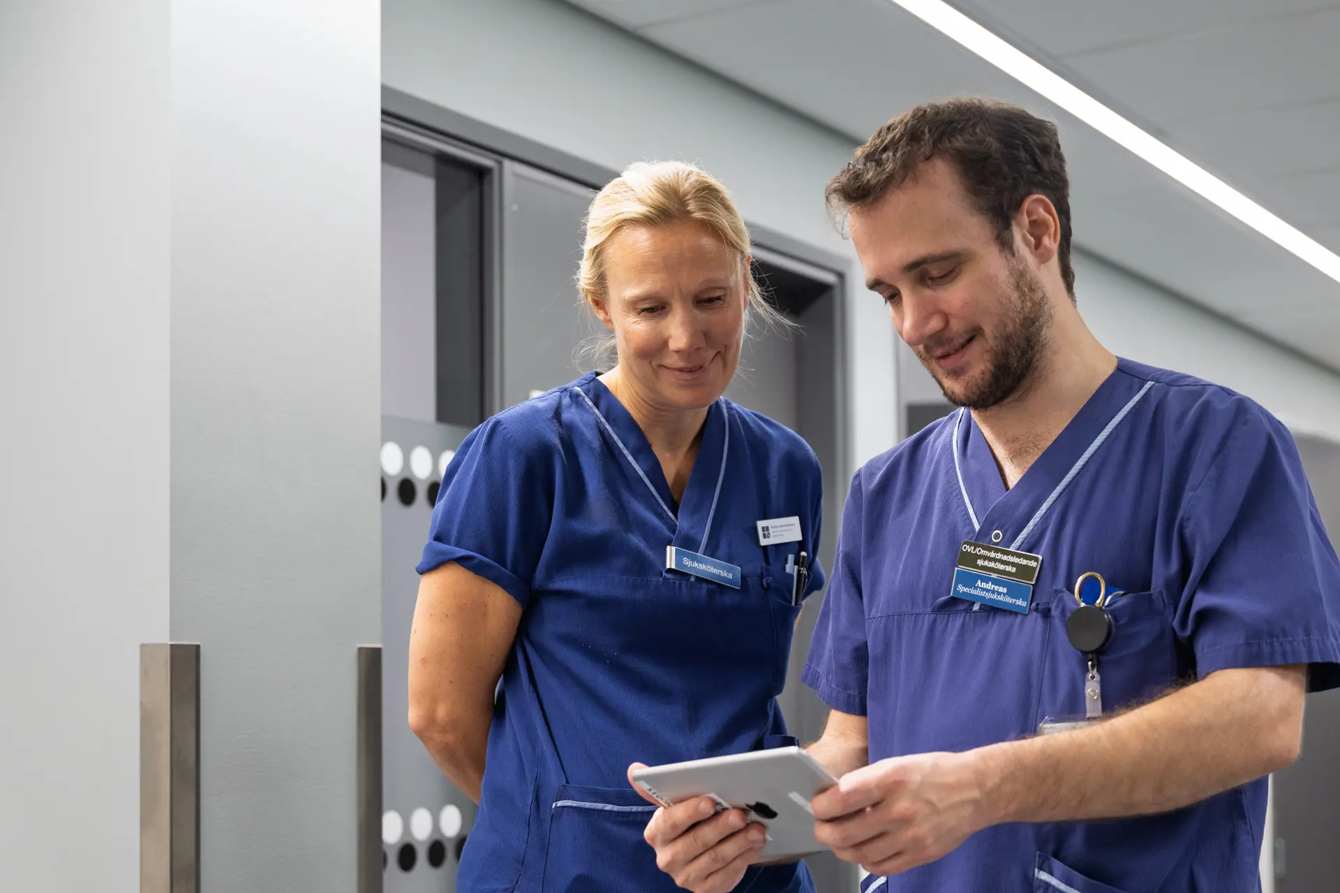 Kristina Lockne-Andersson och Andreas Schenström. Personal visar surfplatta och app.